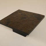 Dark brown stone slab on a beige background