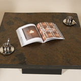 Open magazine on a dark stone coffee table with two silver espresso cups