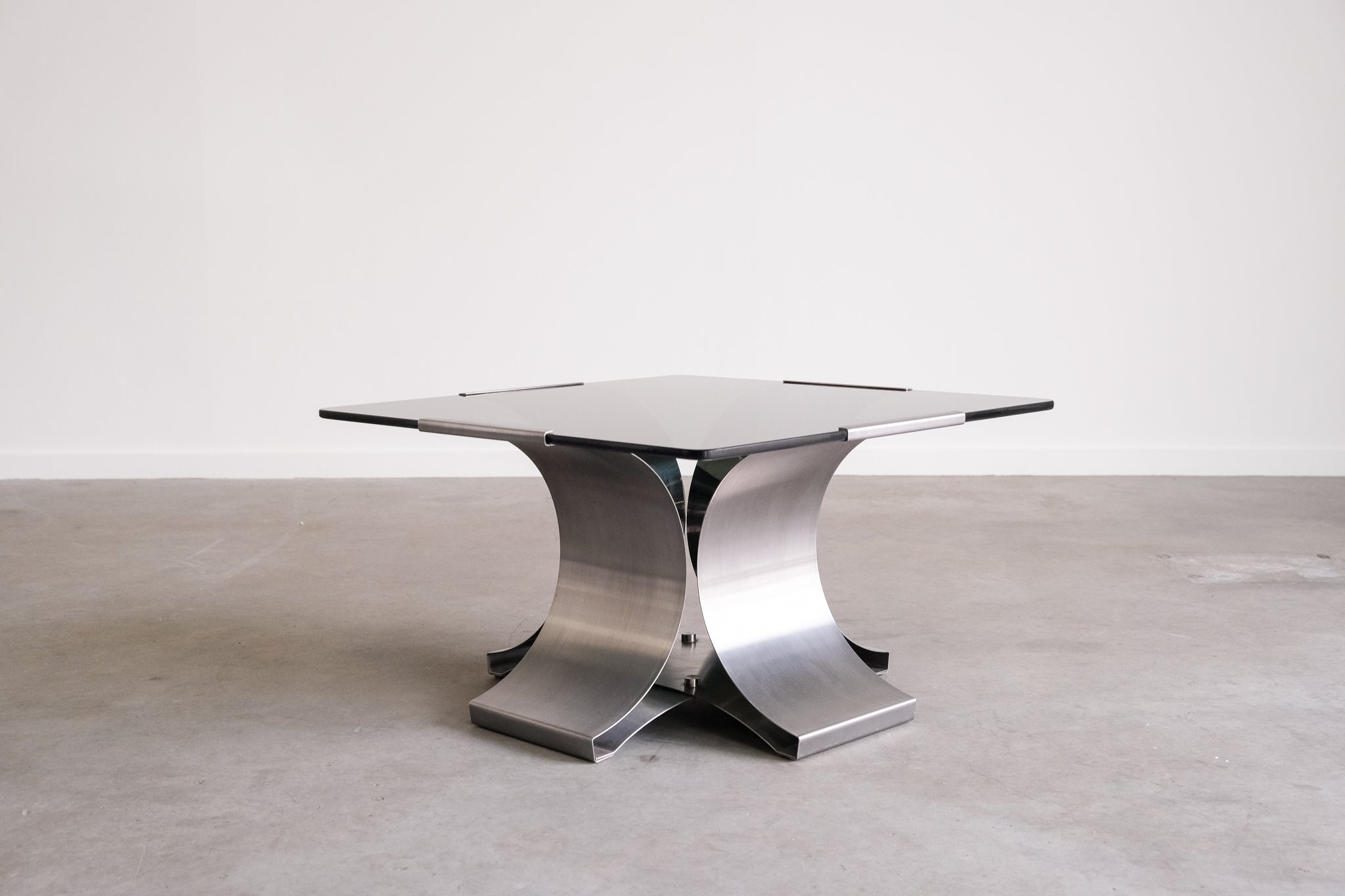 Modern metal table with a glass top on a plain background