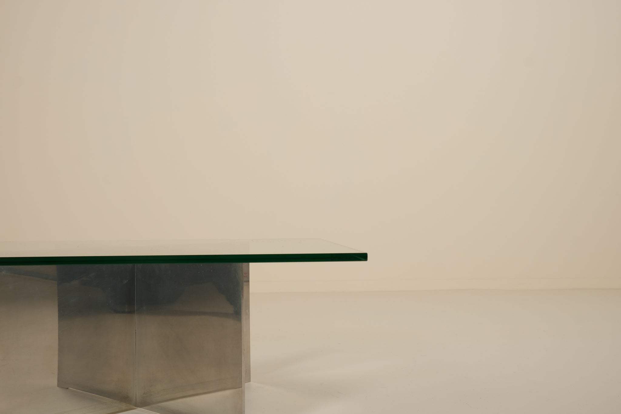 Modern glass table with metallic base on a plain background