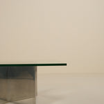 Modern glass table with metallic base on a plain background