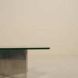 Modern glass table with metallic base on a plain background