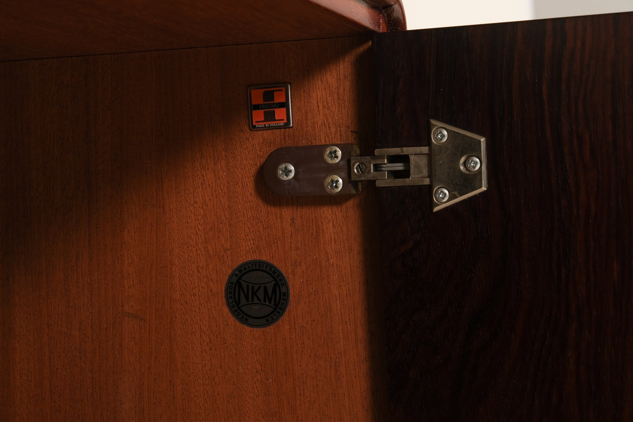 Close-up of a wooden cabinet with a visible brand logo on a dark background