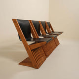 Row of wooden chairs with black leather seats on a beige background
