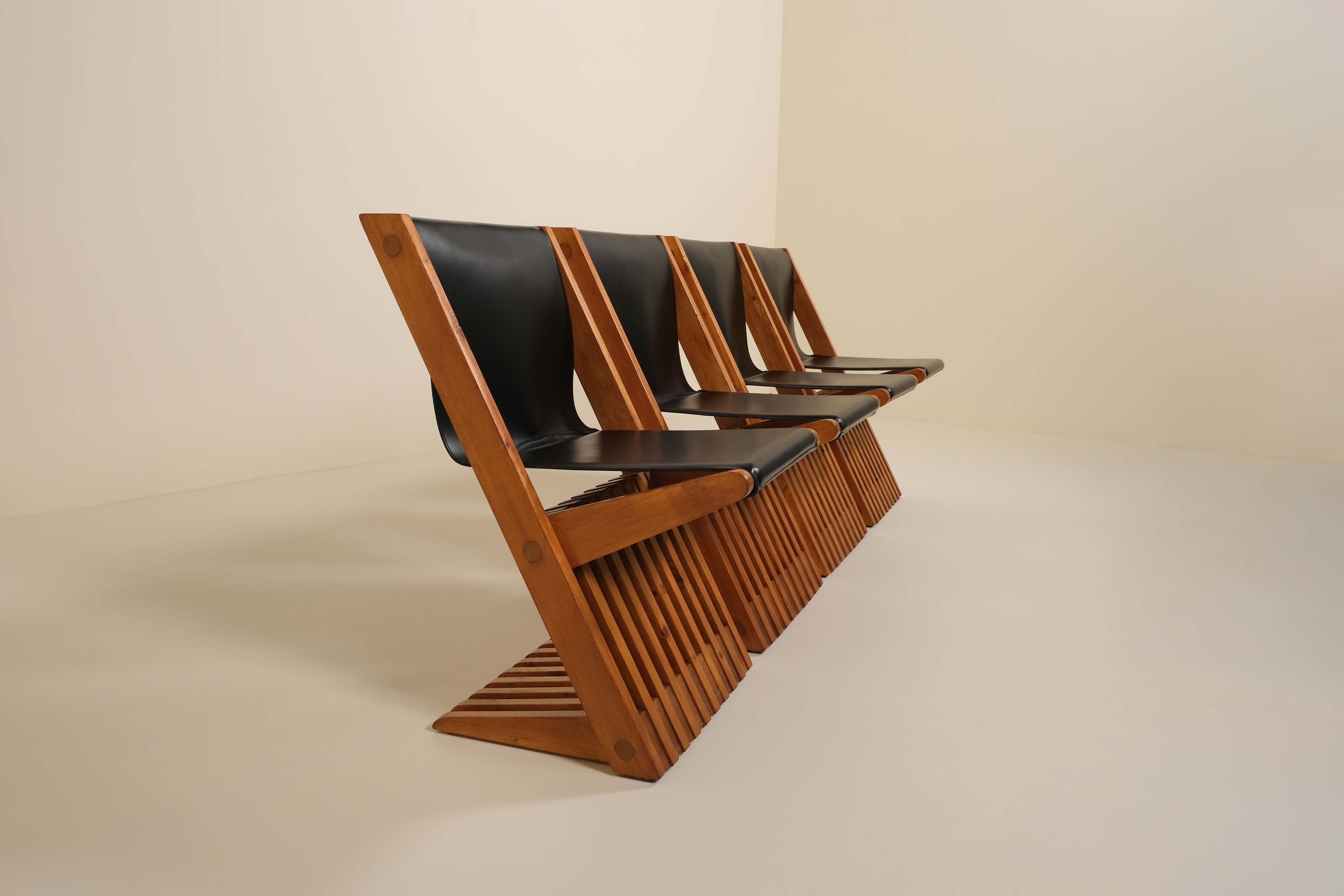 Row of wooden chairs with black leather seats on a beige background