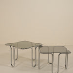 Two glass tables with chrome frames on a beige background