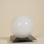 White spherical lamp on a metallic stand against a beige background