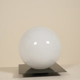 White spherical lamp on a metallic stand against a beige background