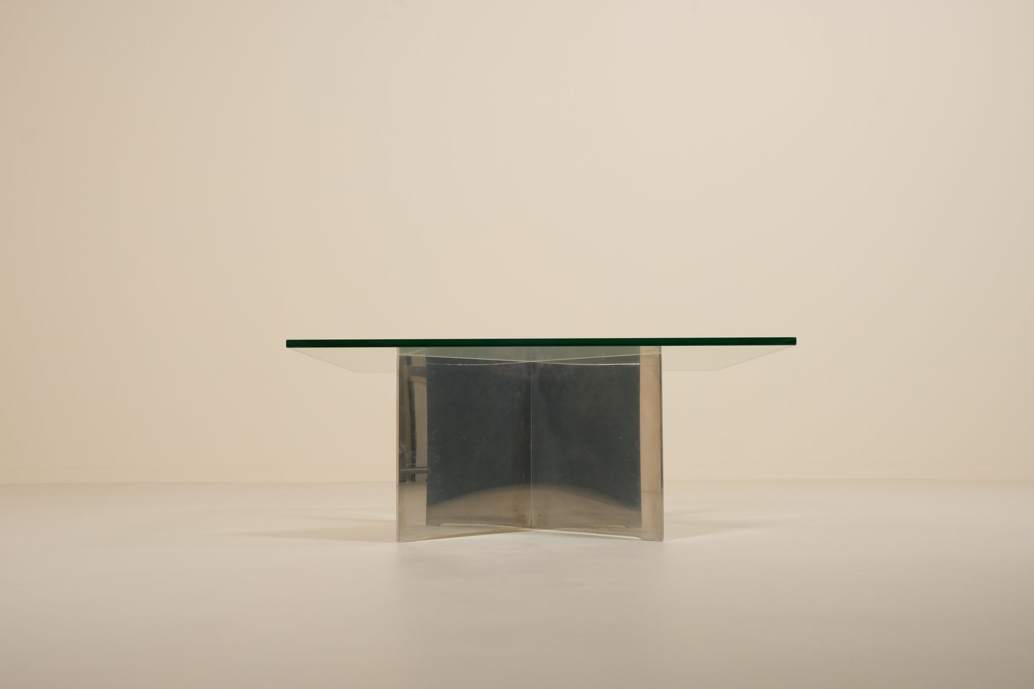 Glass dining table with metallic base on a beige background