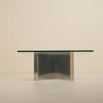 Glass dining table with metallic base on a beige background