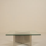 Glass table with metal base on a beige background