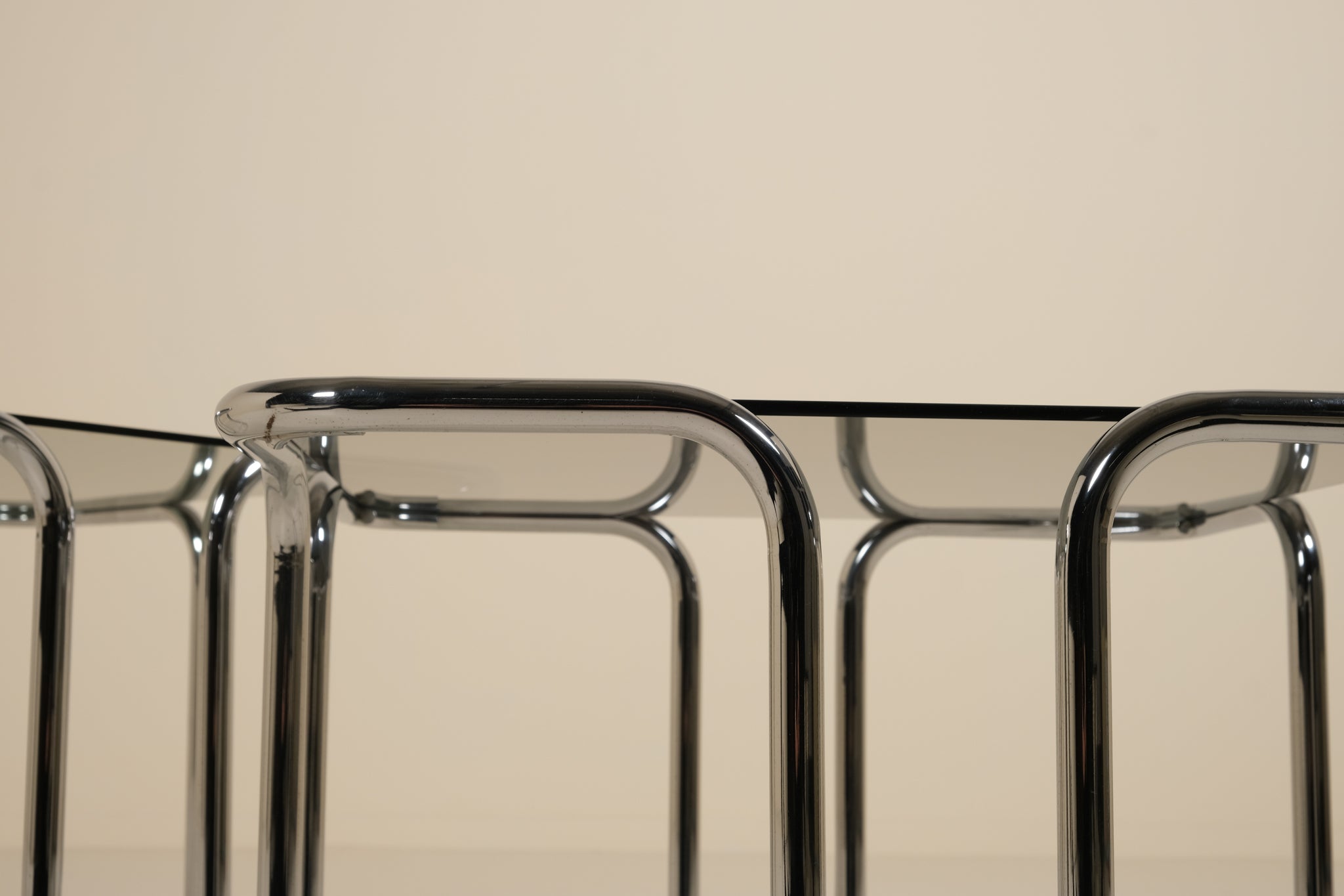 Close-up of a chrome table frame with a beige background