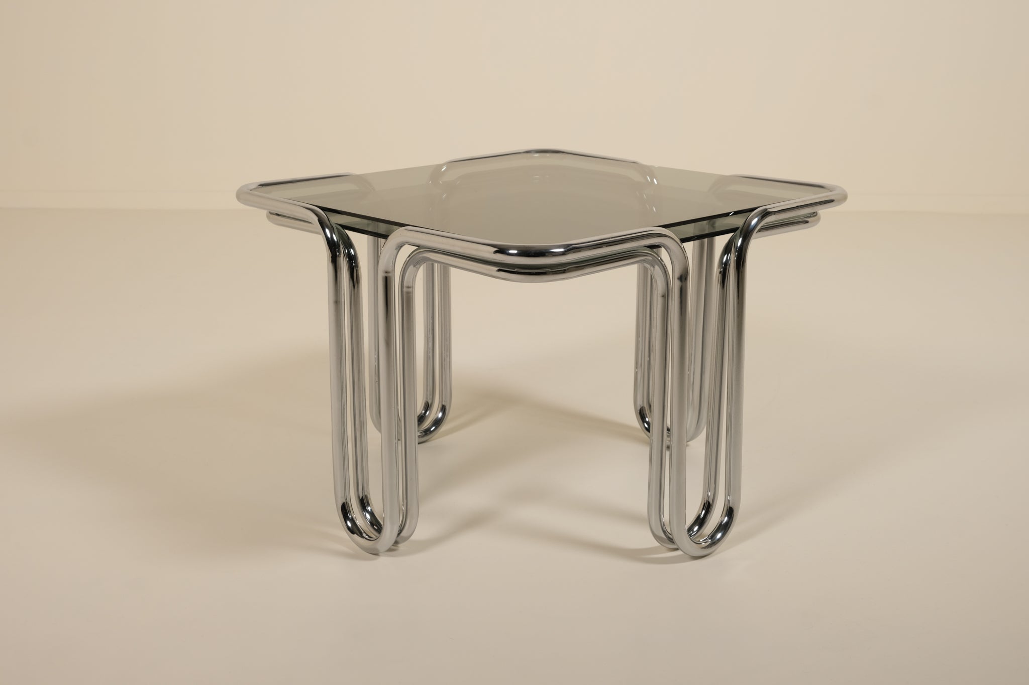 Modern glass table with chrome legs on a beige background