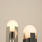 Two modern table lamps with glass shades on a neutral background