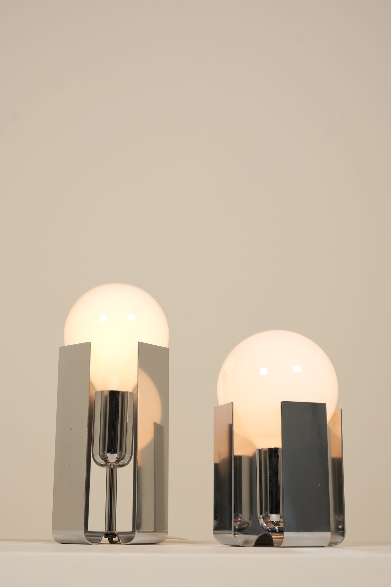 Two modern table lamps with glass shades on a neutral background
