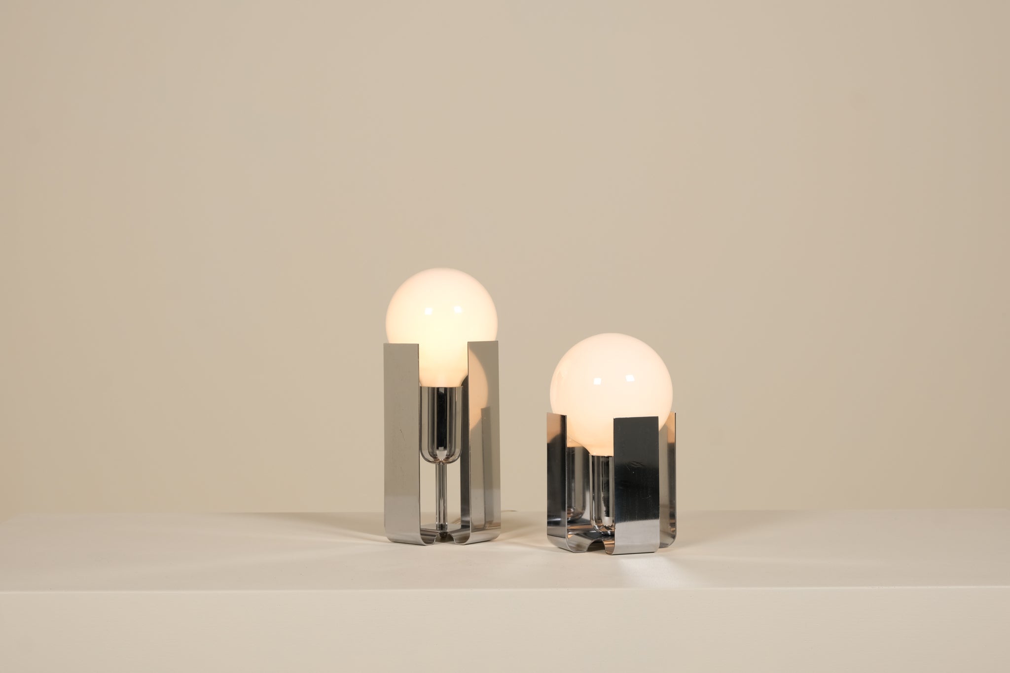 Two modern table lamps with glass shades on a neutral background