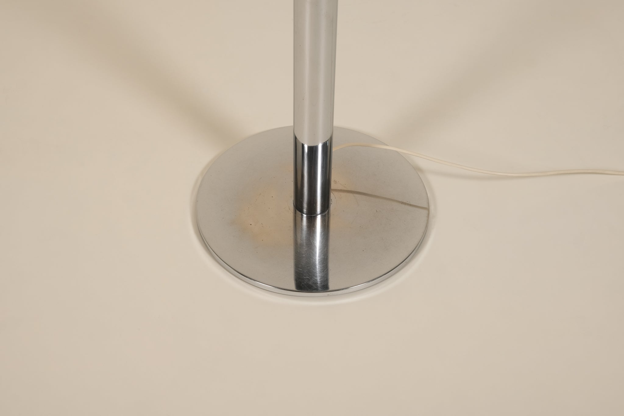 Chrome lamp base on a beige background