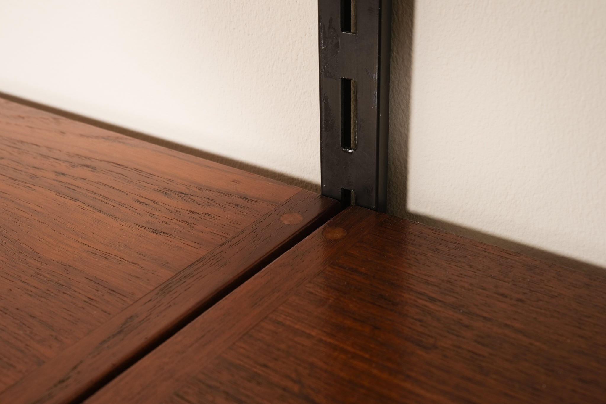 Close-up of a wooden shelf corner with a metal bracket.