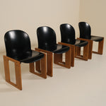 Four black chairs with wooden frames on a beige background