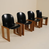 Four black chairs with wooden frames on a beige background