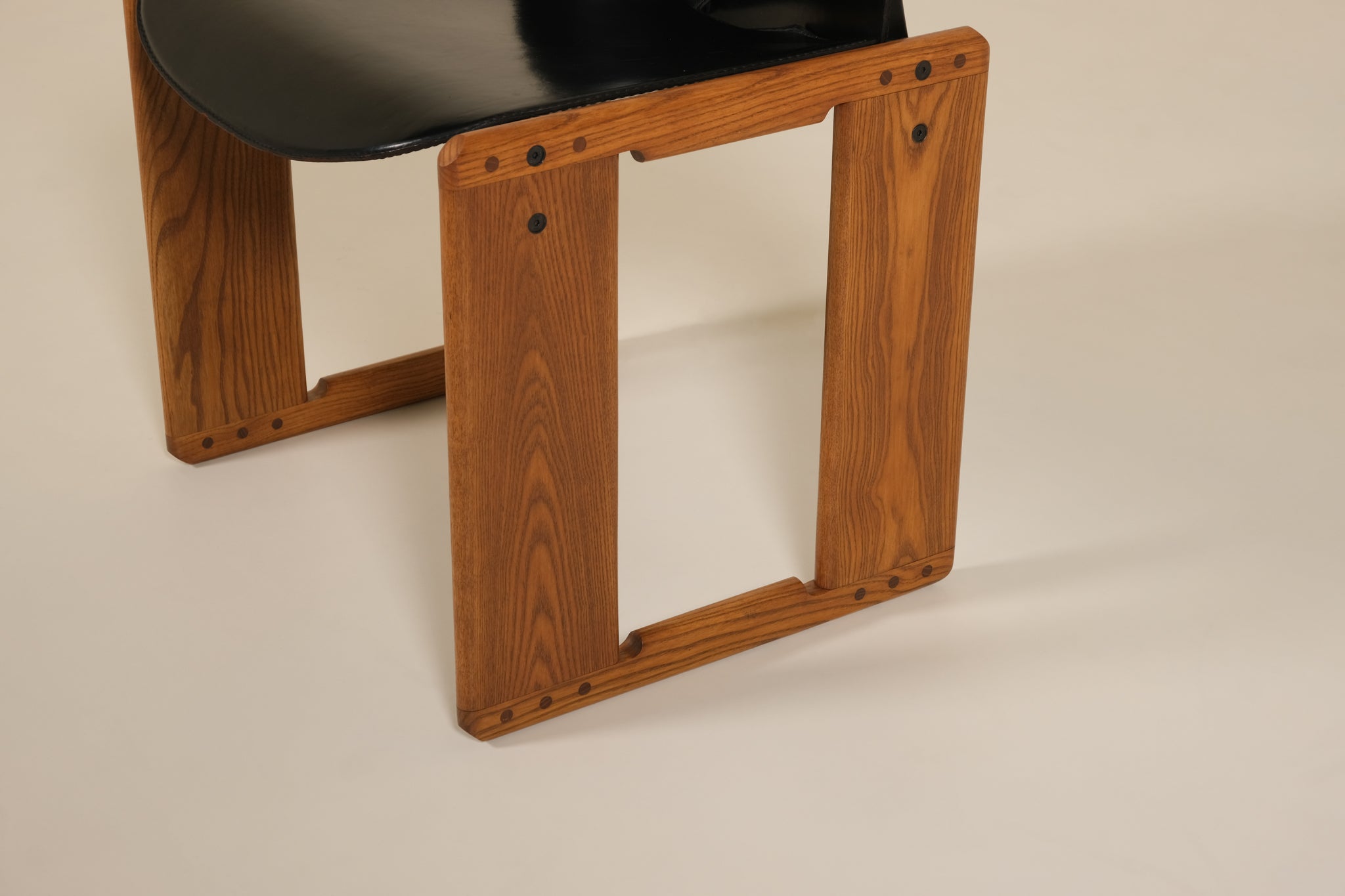 Wooden chair base with a black seat on a beige background