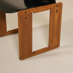 Wooden chair base with a black seat on a beige background