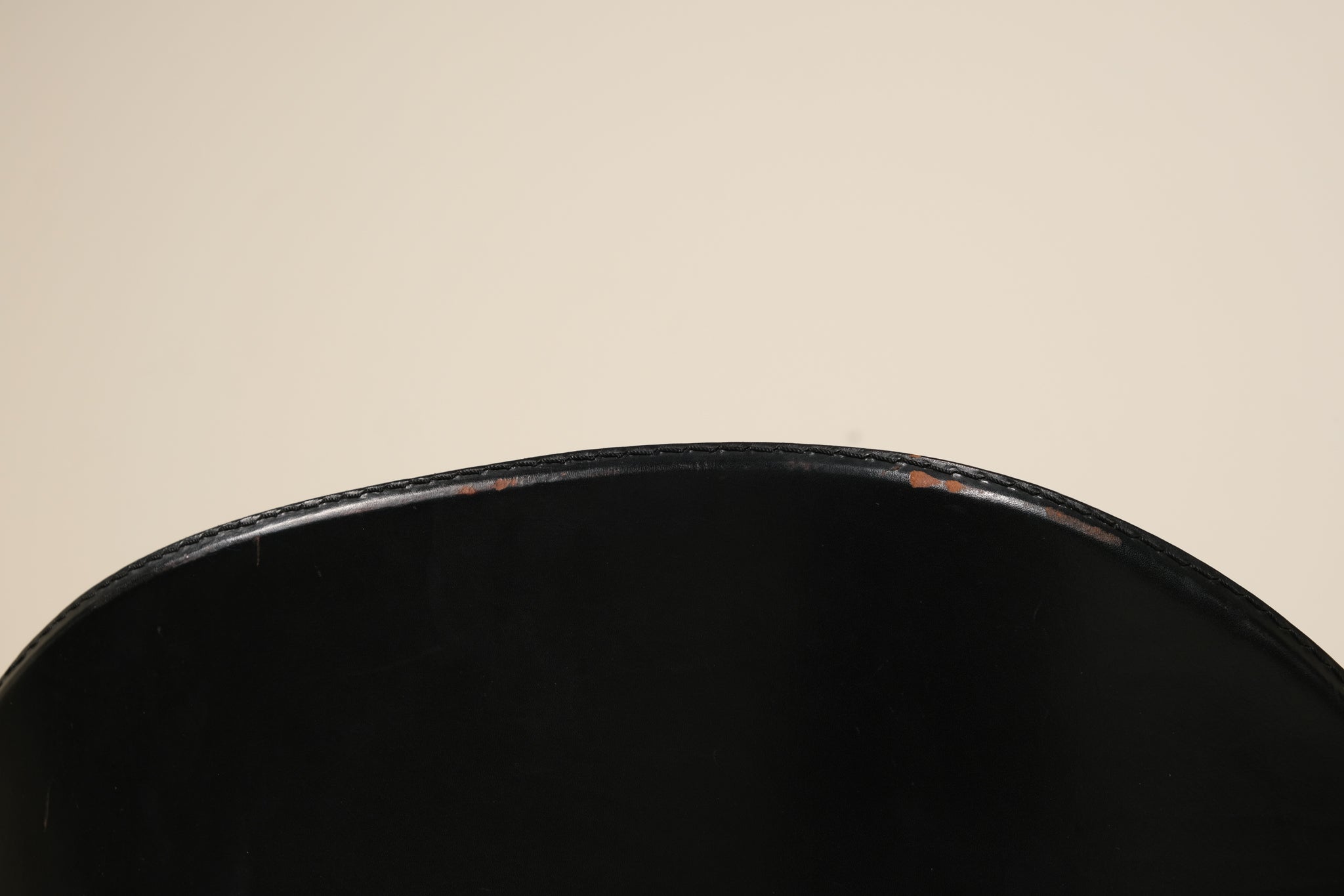 Close-up of a black chair seat on a beige background