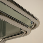 Close-up of a metallic table with a reflective surface on a plain background