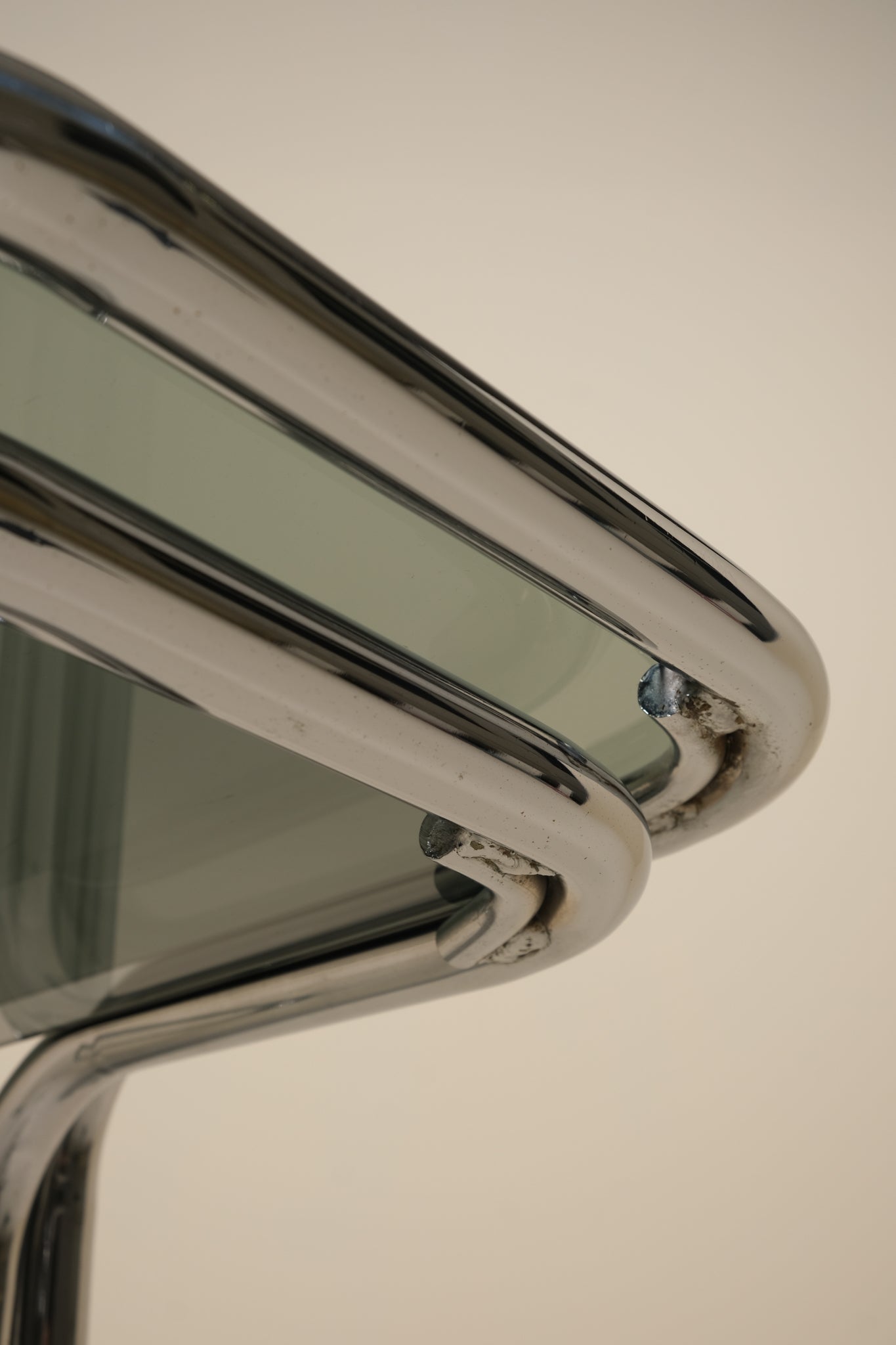 Close-up of a metallic table with a reflective surface on a plain background
