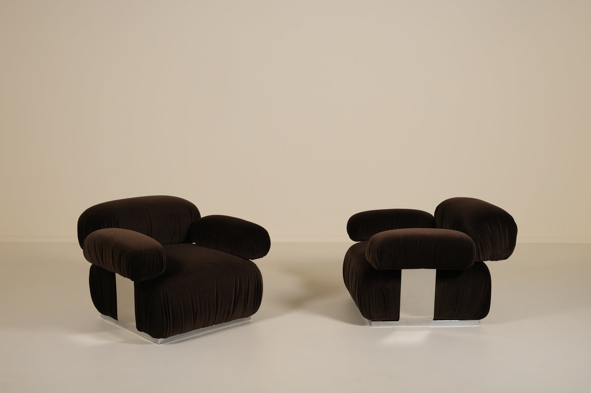 Two dark brown armchairs on a beige background
