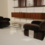 Modern living room with brown armchairs and a glass coffee table.