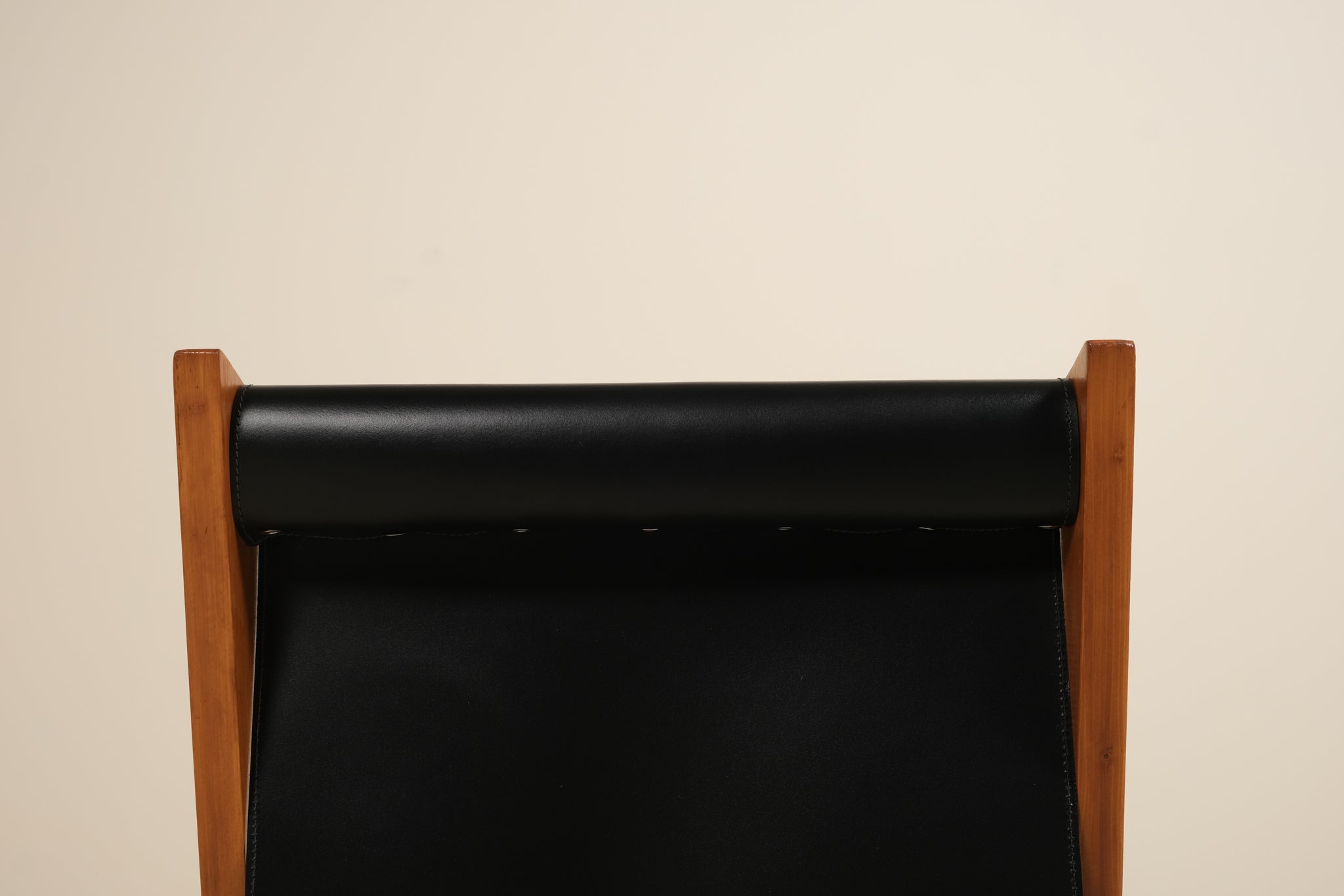 Black leather seat with wooden frame on a beige background