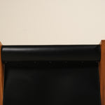 Black leather seat with wooden frame on a beige background