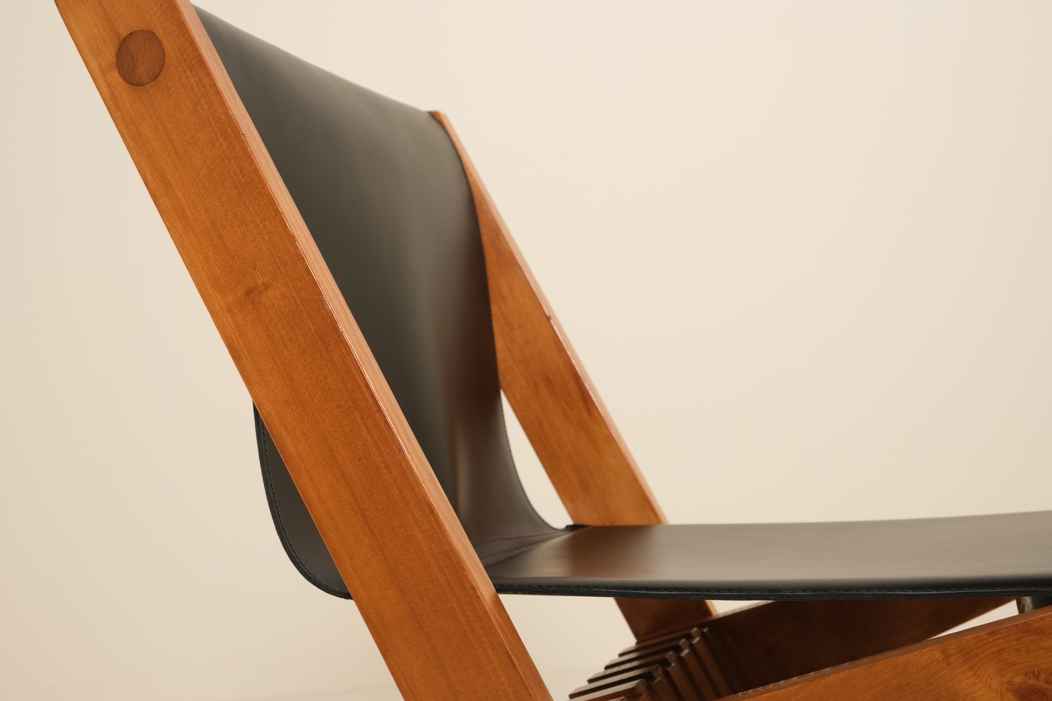 Wooden chair with black seat and backrest on a beige background