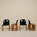 Four black chairs with wooden bases on a beige background