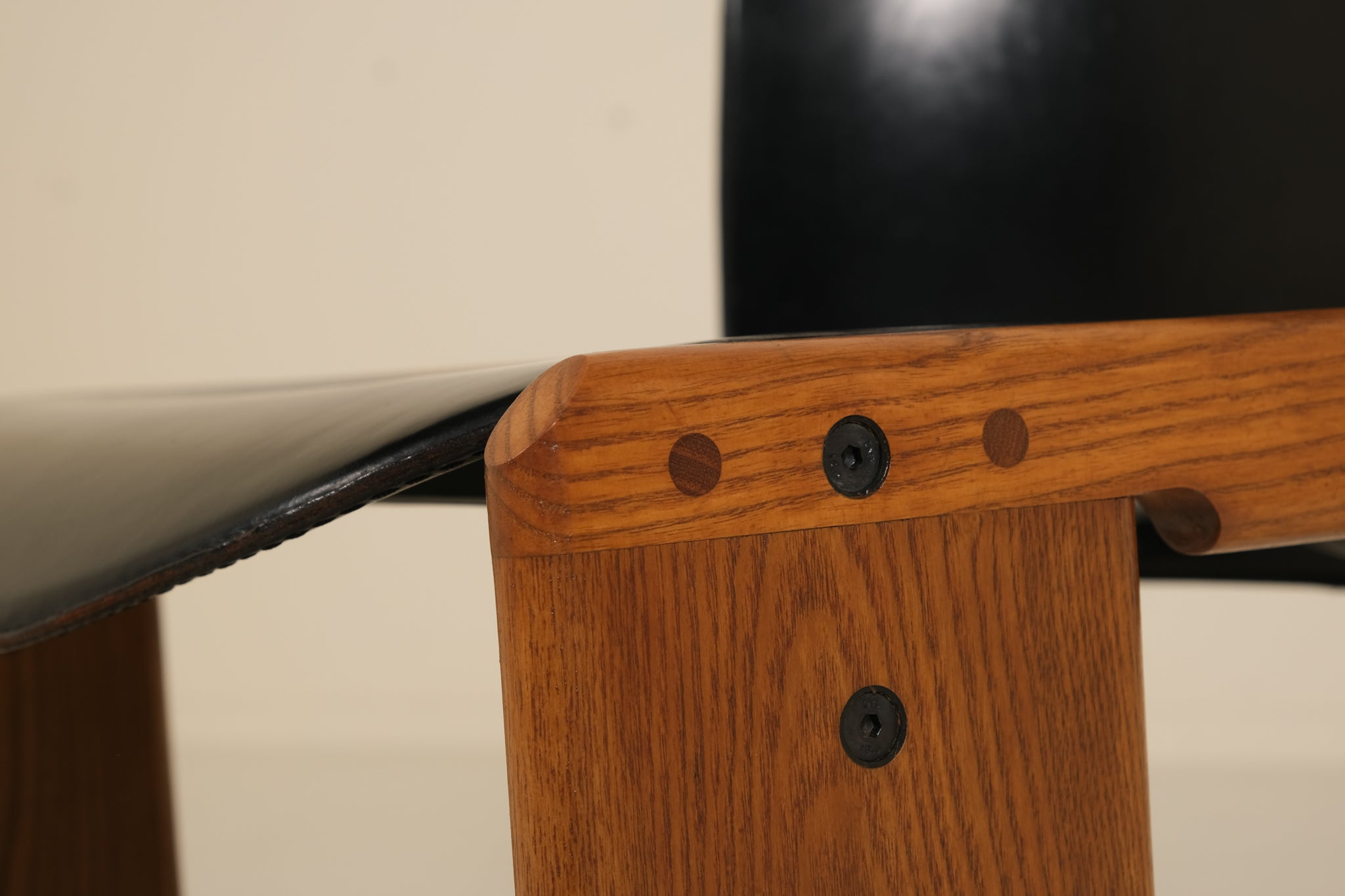 Close-up of a wooden chair with metal screws on a neutral background