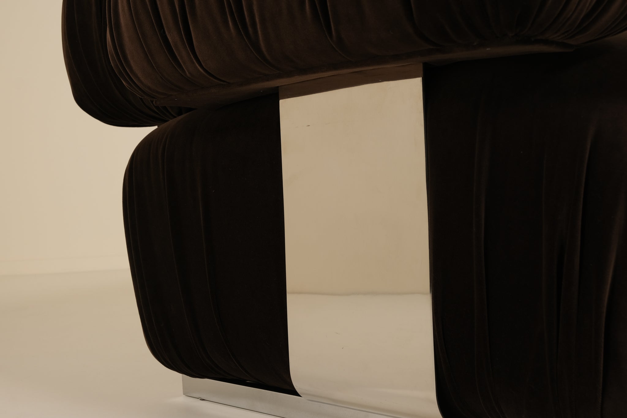 Close-up of a dark brown upholstered chair with a beige background