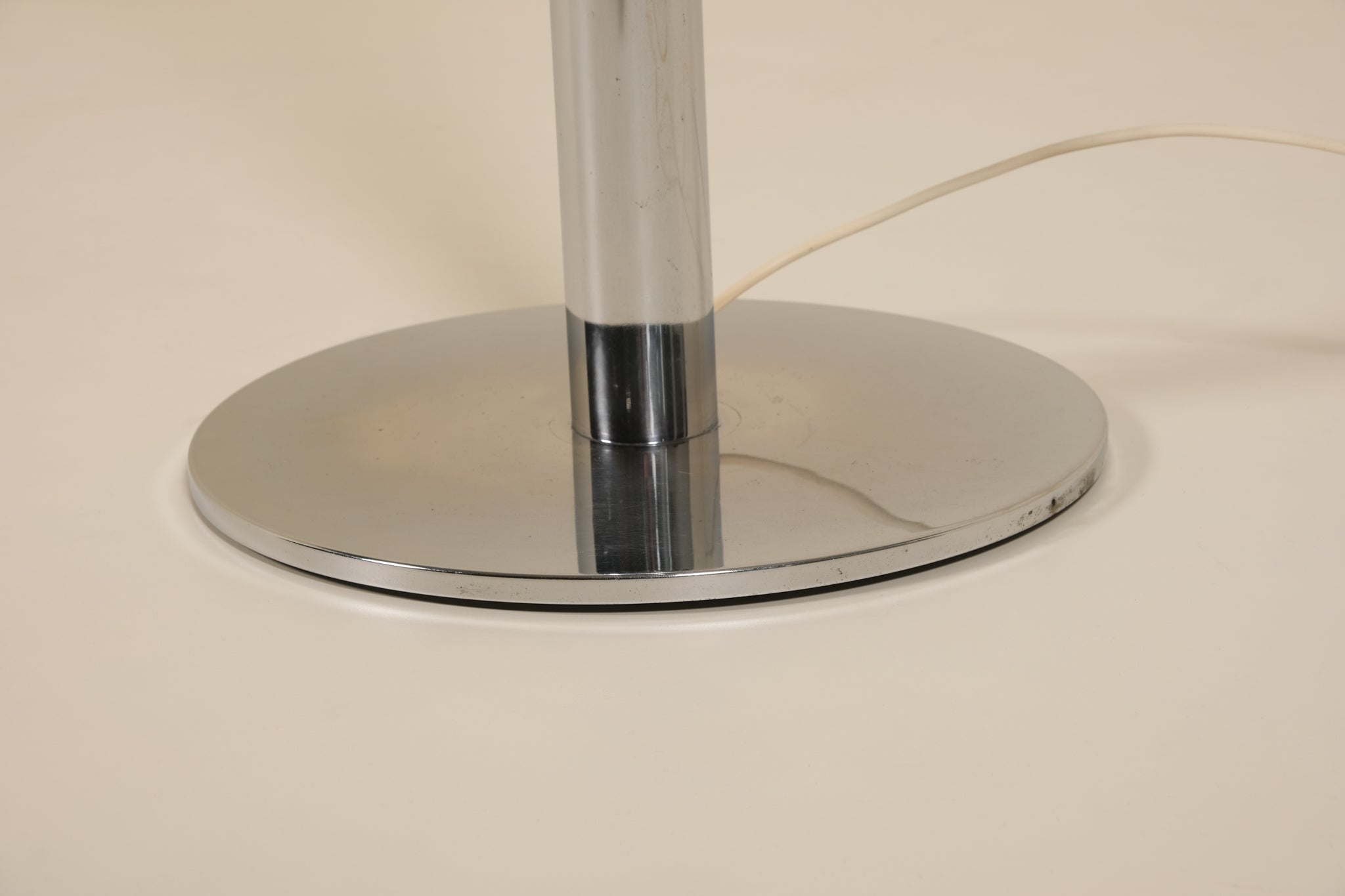 Chrome lamp base on a beige background