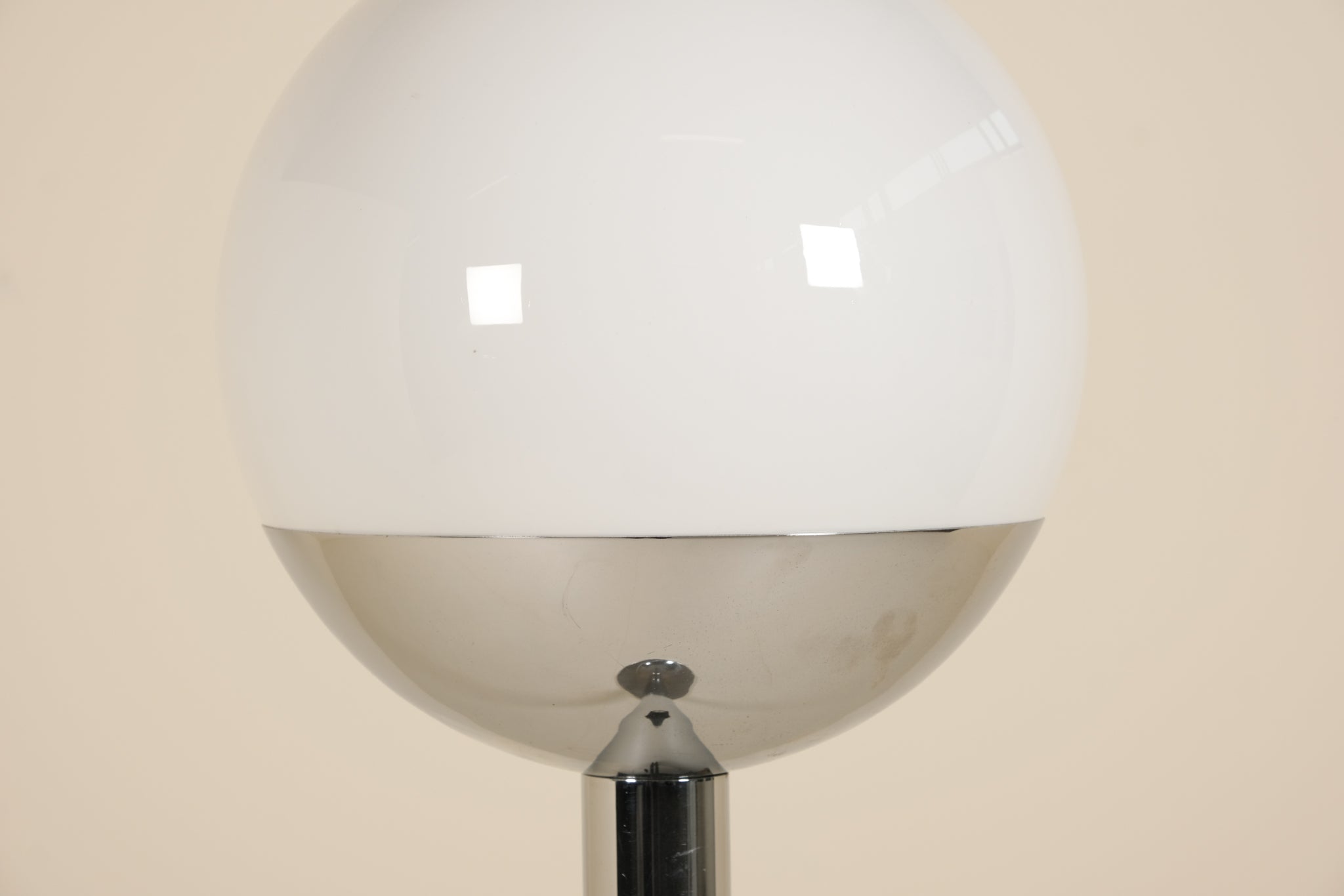 Spherical lamp with a reflective surface on a beige background