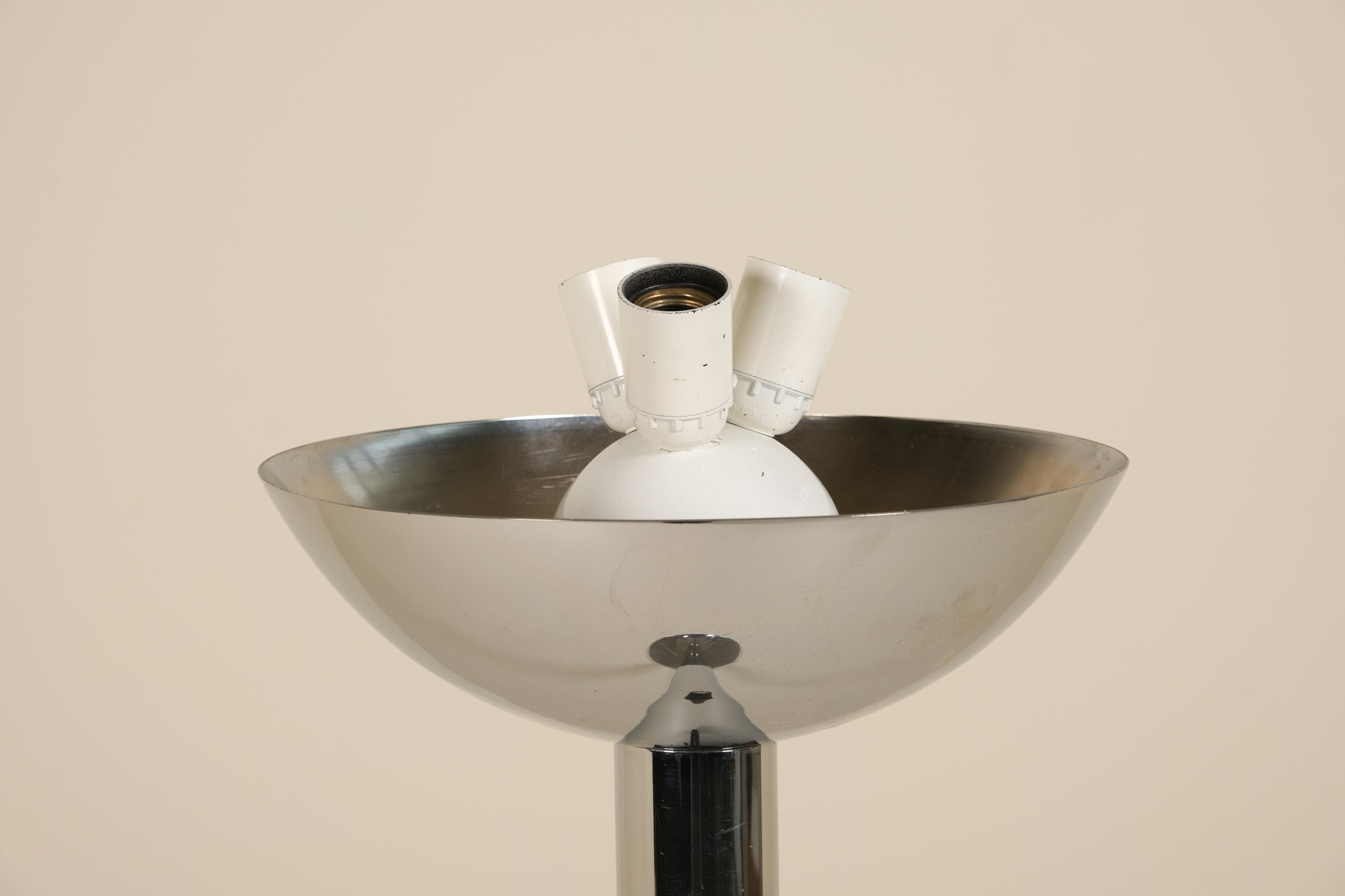 Inside of a chrome floorlamp on a beige background