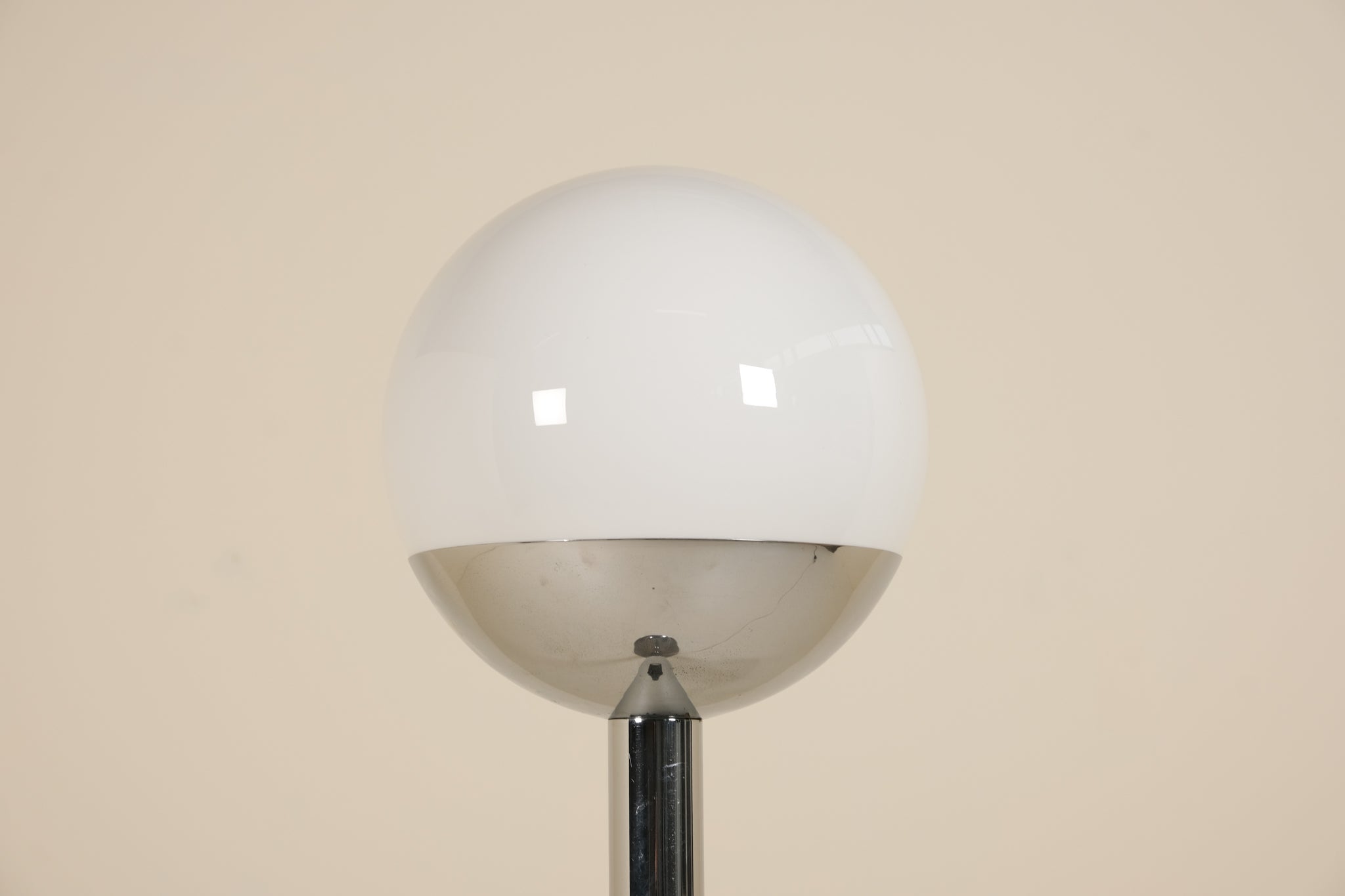 Floor lamp with a large white globe shade against a beige wall