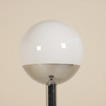 Floor lamp with a large white globe shade against a beige wall