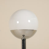 Floor lamp with a large white globe shade against a beige wall