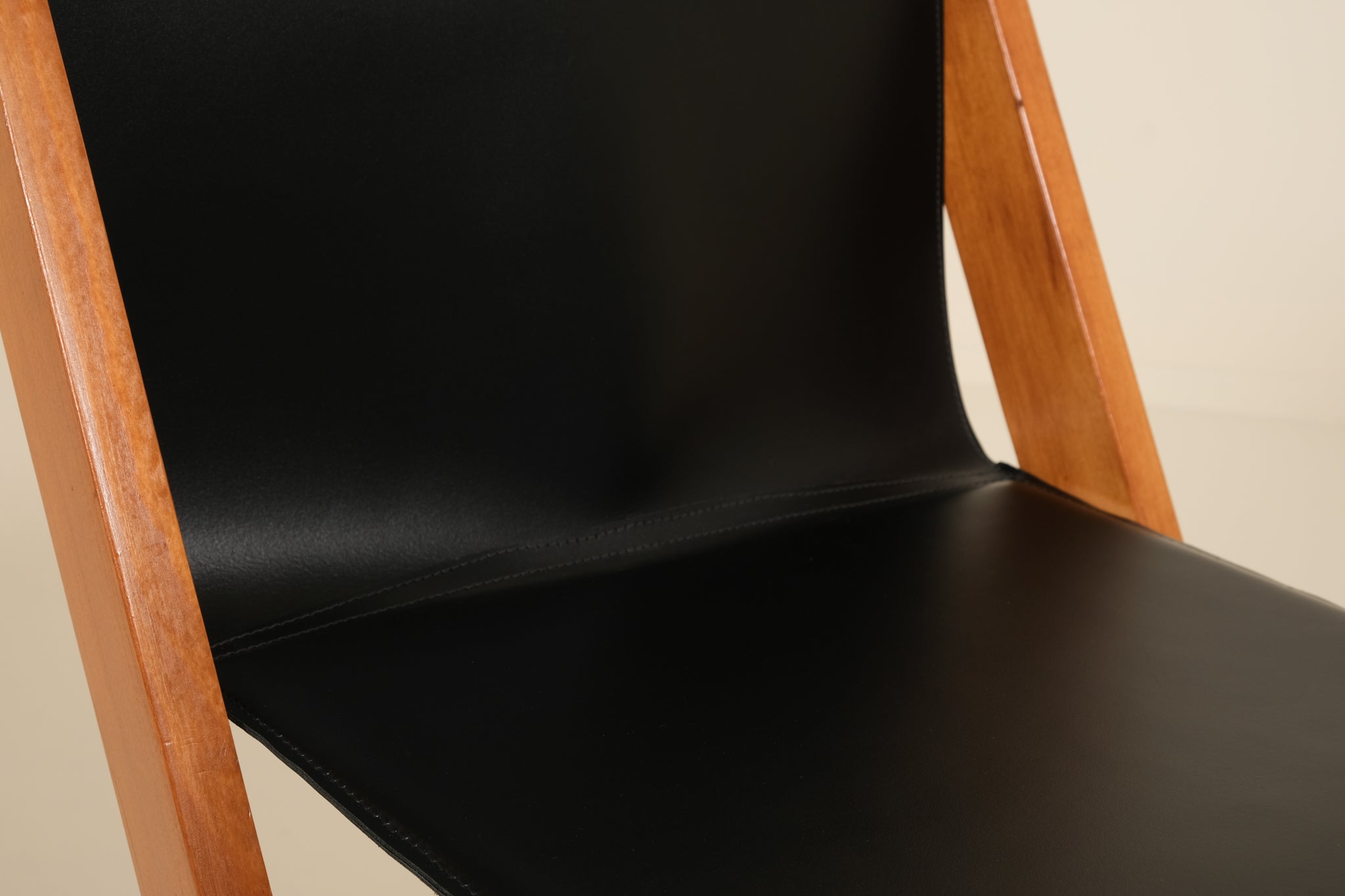 Black chair with wooden frame on a beige background