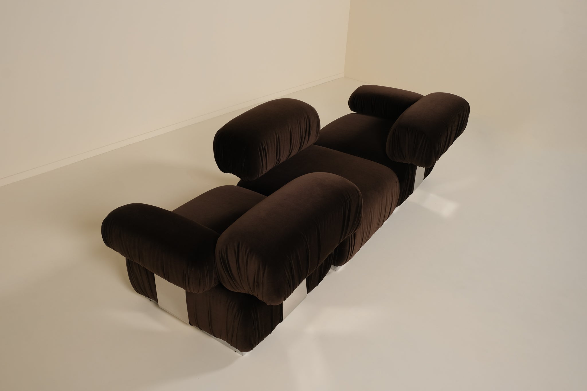 Brown modular sofa on a white floor with a white wall background