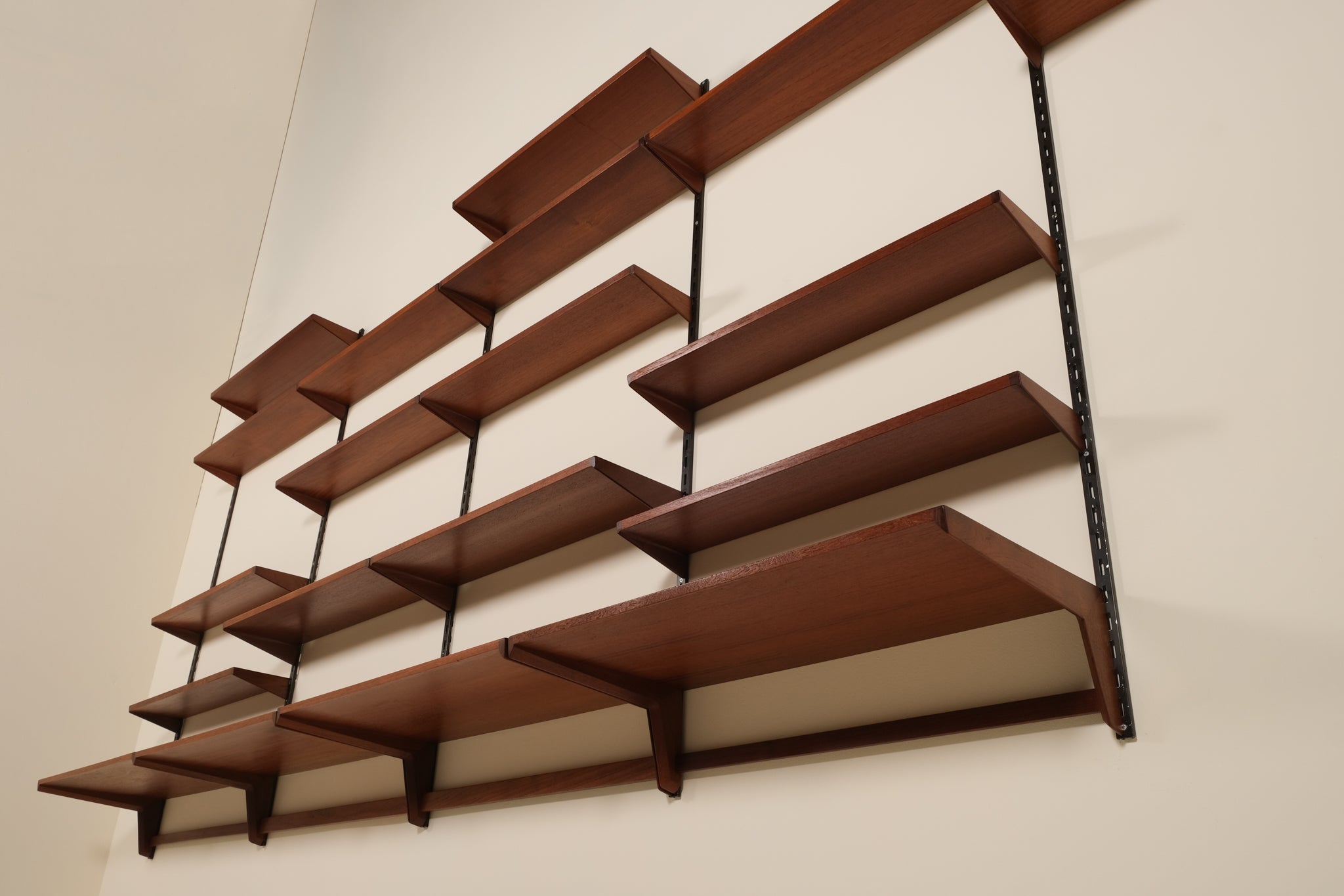 Wooden wall shelf with multiple shelves on a plain wall