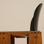 Wooden stool with a black cushioned seat against a beige background