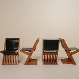 Four modern chairs with black seats and wooden frames on a beige background