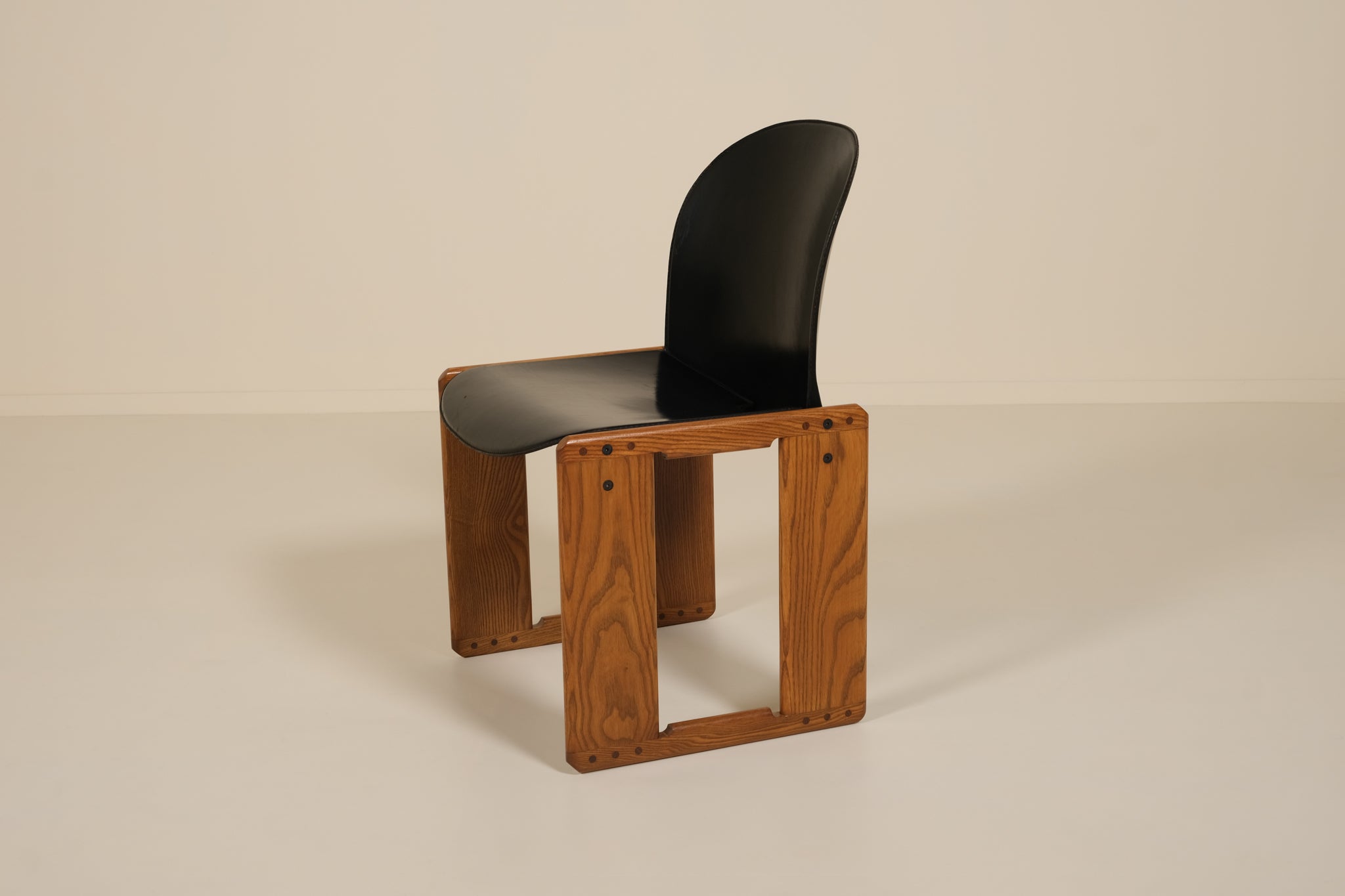 Chair with wooden frame and black seat on a beige background
