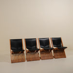 Four black leather chairs with wooden frames arranged in a row on a beige background